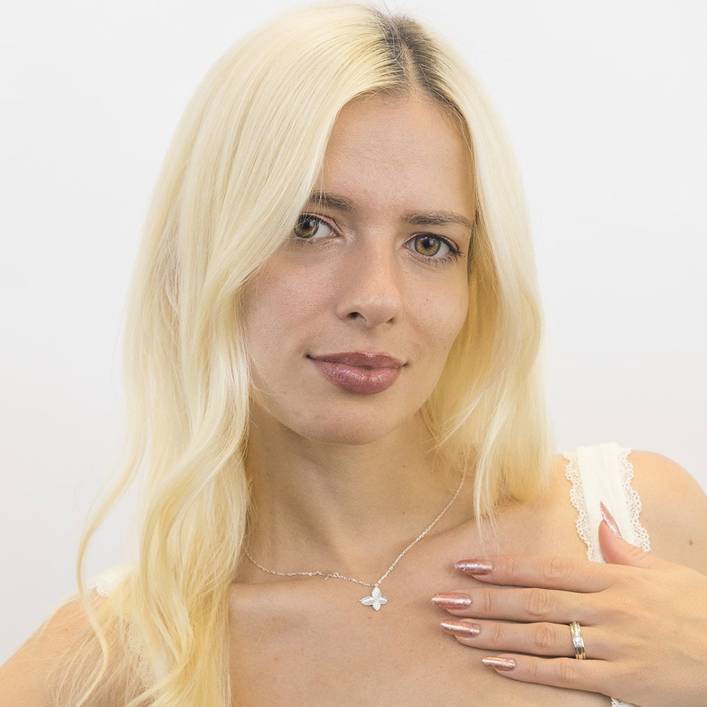Woman with blonde hair wearing a white top against a plain background